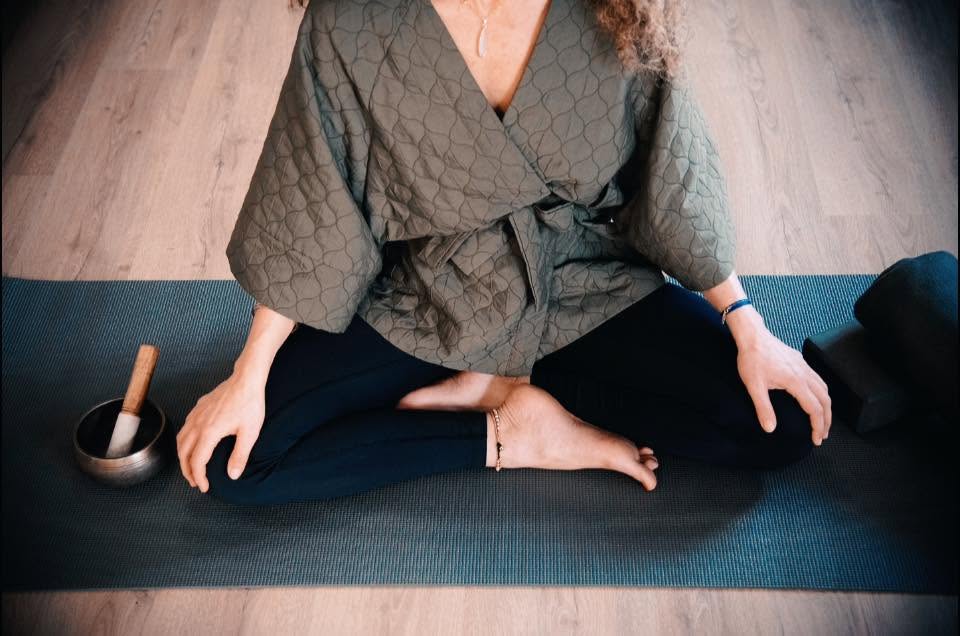 Shohreh siddende i meditation på yogamåtte med syngende skål